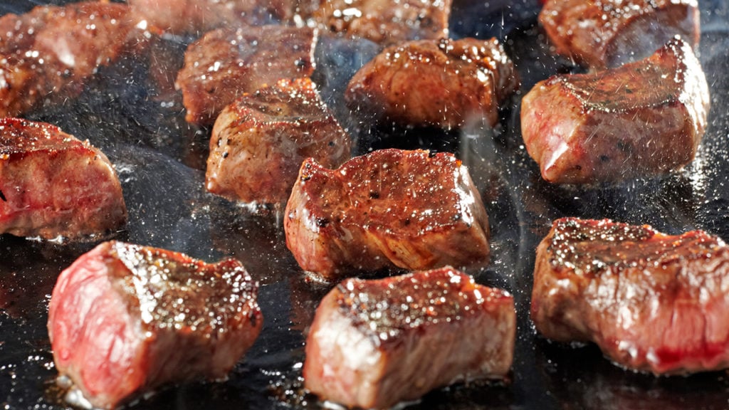steak tips cooking on cast-iron