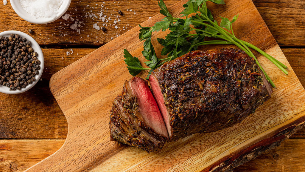 Top sirloin cap coulotte roast on a chopping block with parsley.