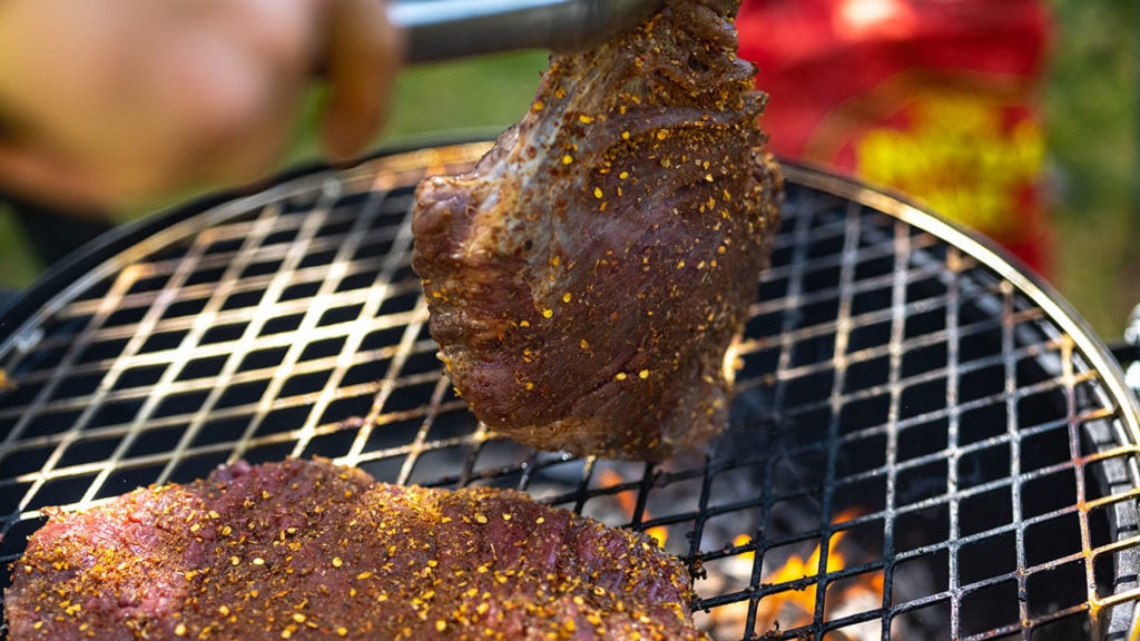 Dry rub flank steaks going on a hot grill.