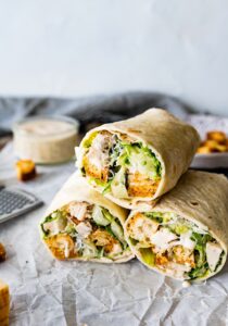 three halves of a chicken Caesar salad stacked on a napkin